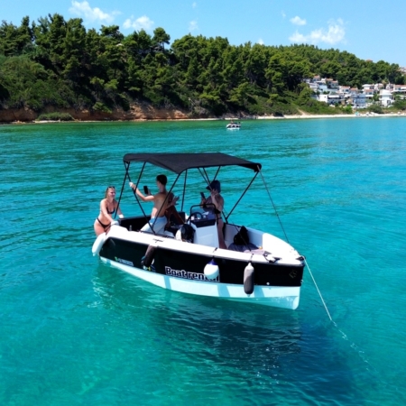 Boat rental without licence in Halkidiki: small motorboat with sun canopy and guests anchored in clear turquoise water